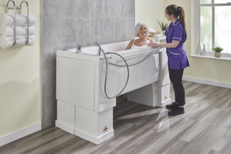 woman in height adjustable bath talking to her carer