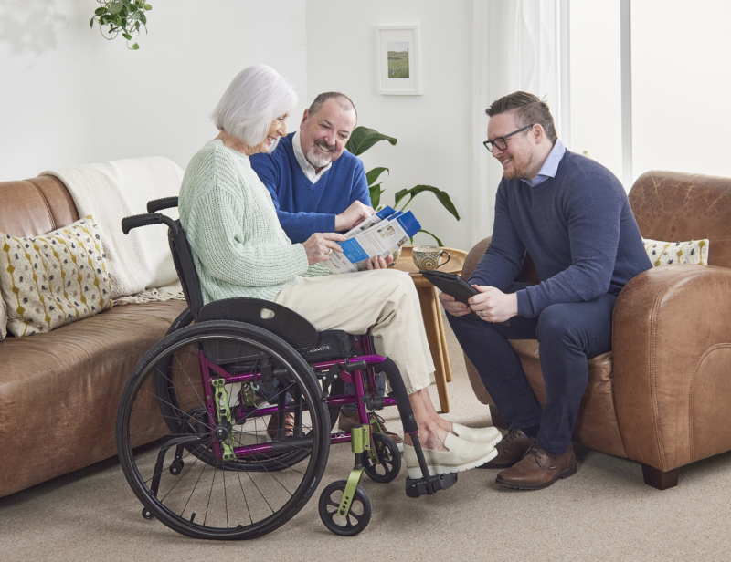 woman in wheelchair talking with salesman about brochure in sitting room